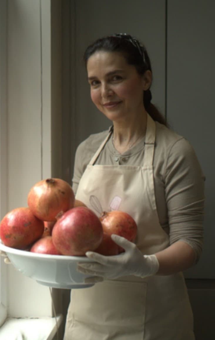 Rana holding a bowl of pomegranates in her kitchen